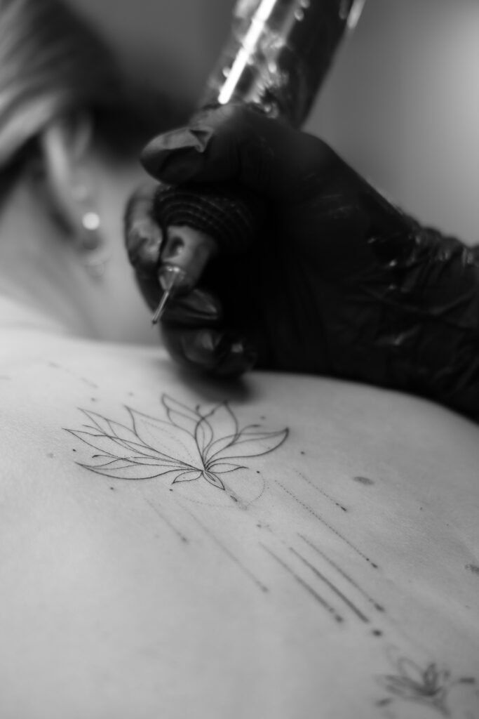 Proces tworzenia delikatnego tatuażu w stylu fine line na plecach. Precyzyjne linie i minimalistyczna kompozycja stworzone w Fineline Tattoo Gallery w Krakowie.